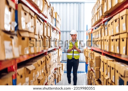 Portrait engineer worker labor man shipping order detail check goods and supplies on shelves with goods background inventory in factory warehouse.logistic industry and business export