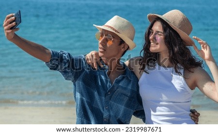 happy young couple taking a selfie with mobile phone on the beach