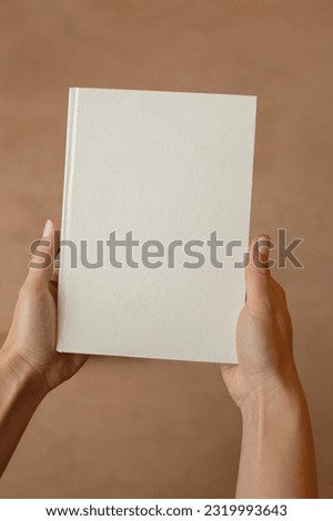 She is holding an empty notebook or book. Mockup book. Blank notebook, blank book Royalty-Free Stock Photo #2319993643
