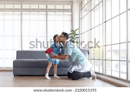 Cute little girl kissing her cheerful handsome dad after dancing together and daddy giving flower bouquet, dad trying to train daughter to dance ballet, family spend time together. Happy Father Day.
