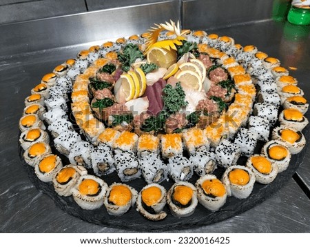 Rolls with tuna, salmon, shrimp, crab and avocado. Top view of various sushi, all-you -can -eat menu. Multicolored sushi are stacked in circle on a black tray.