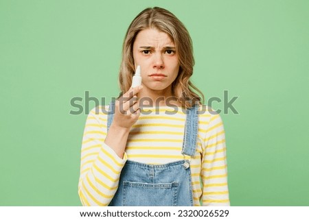 Sick unhealthy ill allergic sad woman has red watery eyes runny stuffy sore nose suffer from allergy trigger symptoms hay fever use nasal spray drops isolated on plain green background studio portrait