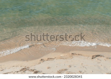 Small waves on the river are lapping against the sandy shore. Wave background on the sand. High angle shot. Sea and river nature background.