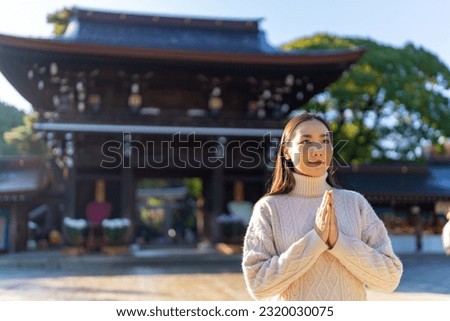 Young Asian woman praying in traditional Meiji Jingu Shrine in Tokyo city, Japan. Attractive girl tourist travel Japan landmark famous place and learning Japanese culture in autumn holiday vacation.