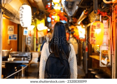 Asian woman shopping at street market and looking for izakaya restaurant at Shinjuku district, Tokyo city, Japan. Attractive girl enjoy and fun outdoor lifestyle travel Japan on holiday vacation. Royalty-Free Stock Photo #2320030099