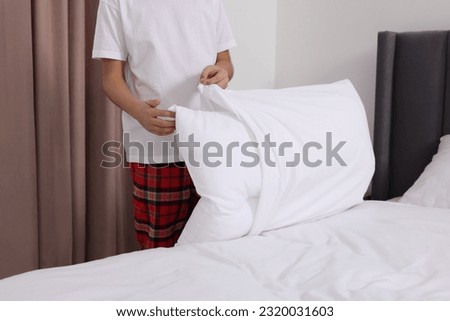 Boy changing pillowcase in bedroom, closeup. Domestic chores Royalty-Free Stock Photo #2320031603