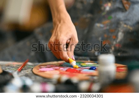 Closeup view of male artist mixing color oil painting on palette. Art, hobby and leisure activity concept