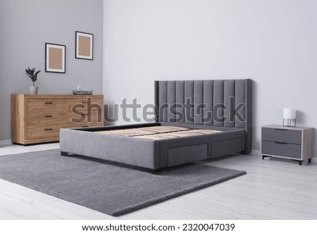 Comfortable bed with storage space for bedding under slatted base in stylish room Royalty-Free Stock Photo #2320047039