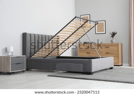 Comfortable bed with storage space for bedding under lifted slatted base in stylish room