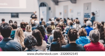 Male speaker giving presentation in lecture hall at university workshop. Audience in conference hall. Rear view of unrecognized participant in audience. Scientific conference event. Royalty-Free Stock Photo #2320052145