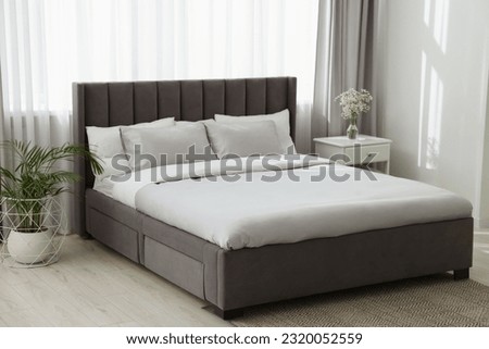 Stylish bedroom interior with comfortable bed, nightstand and beautiful houseplant Royalty-Free Stock Photo #2320052559