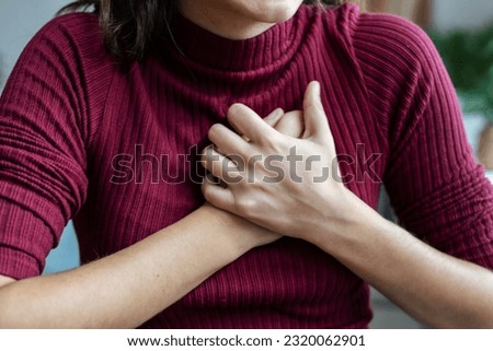 Closeup of woman with chest anxiety and distress putting hands on heart to calm down at home Royalty-Free Stock Photo #2320062901