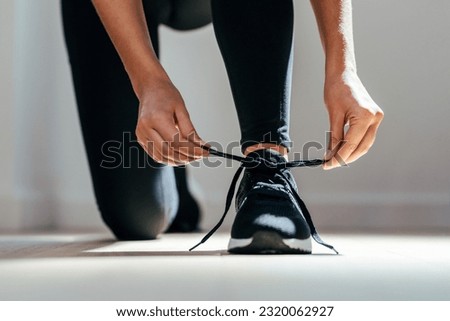 Close up of athletic woman tying her sneakers at home. Royalty-Free Stock Photo #2320062927