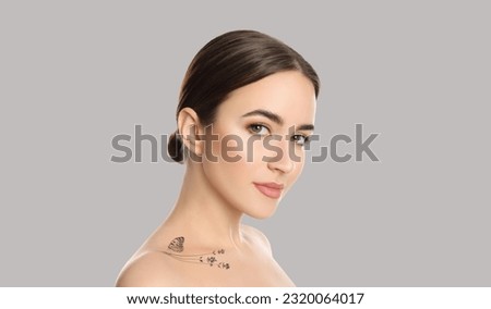 Young woman with beautiful tattoo of flowers and butterfly on light grey background. Banner design