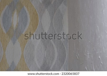 Photo of wall with decorative wallpaper and wall with textured white plaster. Do-it-yourself repair. DIY repair. Gluing and painting.