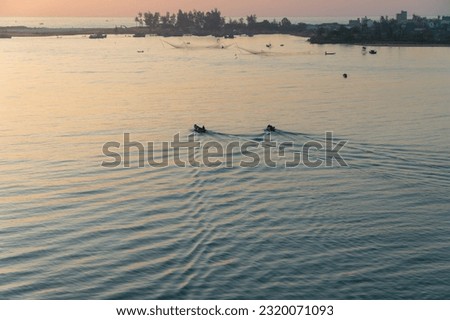 Landscape on the estuary with fishing boats of Vietnamese fishermen, surrounded by clear blue water in the golden morning sun. Angle shot from above. Peaceful nature river concept.