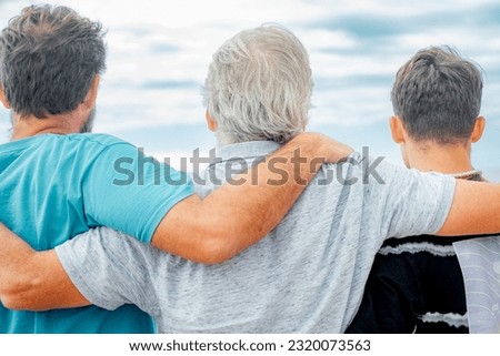 Rear view of family multi generation, father, teenage son and grandfather hugging with love. Handsome people relaxing together Royalty-Free Stock Photo #2320073563
