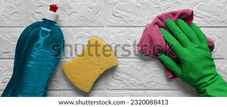 Banner with housewife hand and rag. Routine work in kitchen.  Hand in rubber glove wipes white brick wall with microfiber dishcloth. Flat lay. Cleaning process. Header for cleaning company.