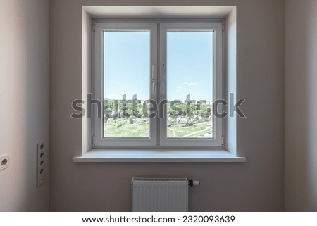 The window in the apartment overlooks the green forest and the blue sky. Royalty-Free Stock Photo #2320093639