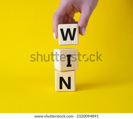 Win symbol. Wooden blocks with words Win. Businessman hand. Beautiful yellow background. Business and Win concept. Copy space.