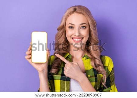 Photo of sweet cute lady wear plaid yellow shirt pointing finger modern device empty space isolated violet color background