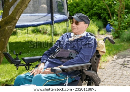 Senior man of 85 years in an electric wheelchair is sitting in a park. Behind him are trees and greenery Royalty-Free Stock Photo #2320118895