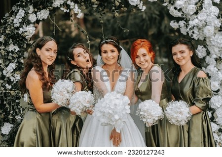 Bridesmaids smiling together with the bride. The bride and her fun friends celebrate the wedding after the ceremony in matching dresses. Bride and friends in nature Royalty-Free Stock Photo #2320127243