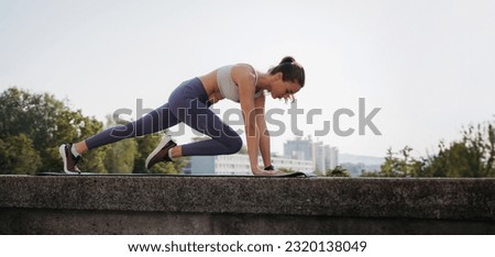 Side view of young sporty woman doing mountain climbers on gym mat in the city. Royalty-Free Stock Photo #2320138049