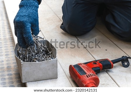 Close up Close up handyman with glove holding screws from box ready to do floor installation in house renovation Royalty-Free Stock Photo #2320142131