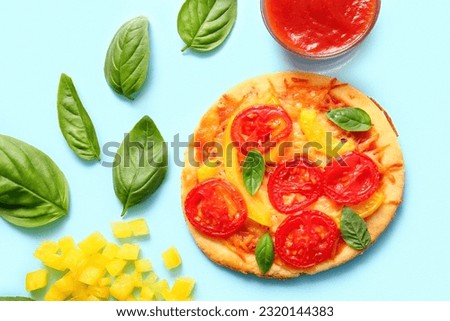 Tasty mini pizza with ketchup on blue background