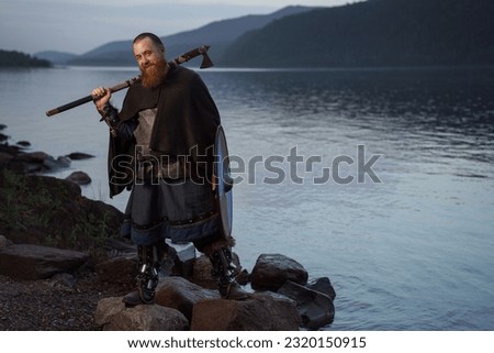 Medieval warrior viking barbarian with ax and shield on shore.