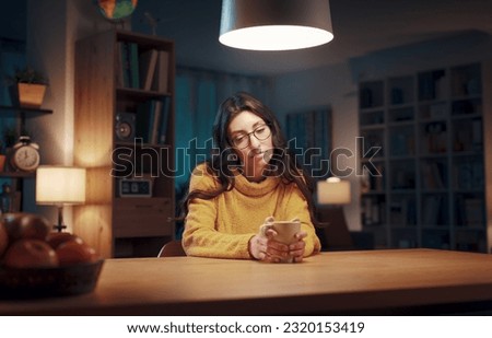 Young pensive woman sitting in the living room at night and drinking coffee Royalty-Free Stock Photo #2320153419