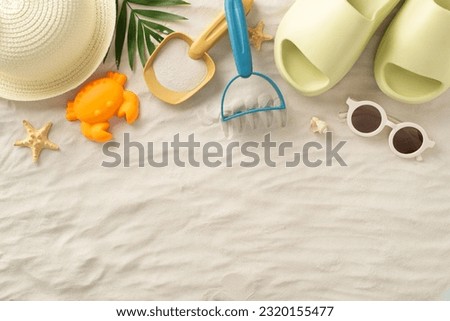 Memories of a summer trip to the sea with children: Top view picture featuring sunhat, kids' sand toys, palm leaf, seashells, slippers and sunglasses on isolated sand background with copyspace