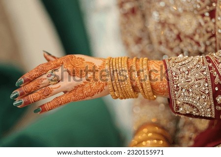 Pakistani Bride's Showing Her  Mehndi And Wedding Ring And Beautiful gold Bangles In Traditional Dress Royalty-Free Stock Photo #2320155971