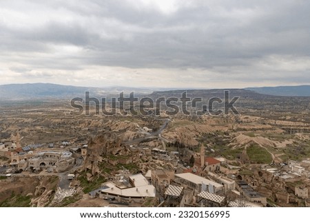 A picture of the Goreme Historical National Park in the background, and the town of Uchisar in the foreground, on a cloudy day.