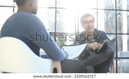 Thoughtful business man in formalwear holding paper while sitting at chair fills out a resume questionnaire in office