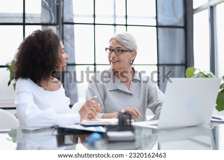 Female colleagues met in the office hall discussing work issues