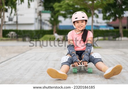 asian child skater or kid girl smile playing skateboard or sitting on surf skate board and fun in skate park for extreme street sports to people wears helmet elbow wrist knee guard for body safety