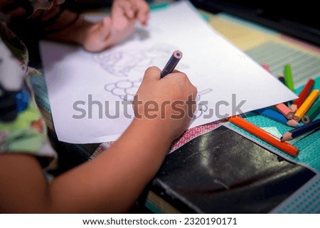 a photo of someone's hand coloring a picture with colored pencils