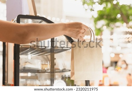 Waitress at counter giving eco friendly paper bag in cafe Royalty-Free Stock Photo #2320211975