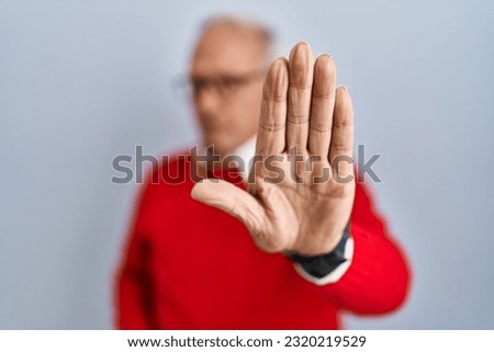 Senior man with grey hair standing over isolated background doing stop sing with palm of the hand. warning expression with negative and serious gesture on the face. 