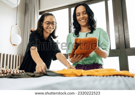 Mom and teen daughter bond as they fold laundry in bed, creating cherished memories through shared chores Royalty-Free Stock Photo #2320222523