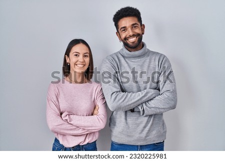 Young hispanic couple standing together happy face smiling with crossed arms looking at the camera. positive person.  Royalty-Free Stock Photo #2320225981