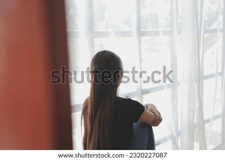 Thoughtful girl sitting on sill embracing knees looking at window, sad depressed teenager spending time alone at home, young upset pensive woman feeling lonely or frustrated thinking about problems Royalty-Free Stock Photo #2320227087