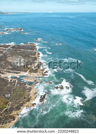 Aerial view of the coastline of Dunbar Scotland with waves crashing onto the rocks. 