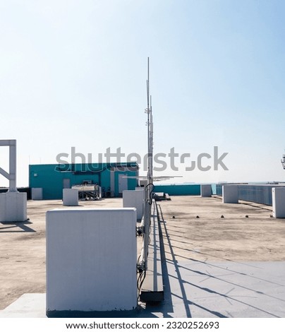 Rooftop small radio television communication tower antenna. Sky with bright sunlight is background. Is device that converts electricity into electromagnetic waves. Modern future technology.