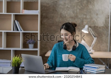 Asian female high school student learning and watching online course on laptop at home. Young female student studying in online classroom with teacher at home