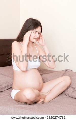 Young pretty pregnant woman suffering from headache at home in bed.
