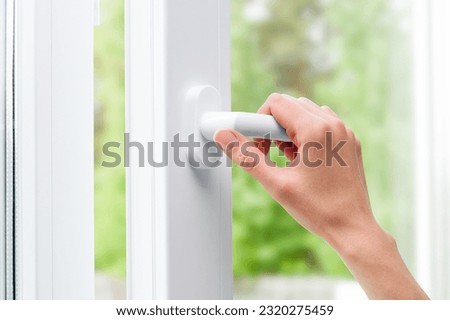 female hand opens a plastic window in a home room (PVC plastic) Royalty-Free Stock Photo #2320275459