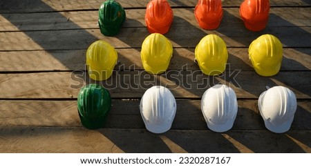 Safety helmet (hard hat) for engineer, safety officer, or architect, place on wooden floor. Yellow, White, green, blue, and orange safety hat (helmet) on construction site-banner  image.